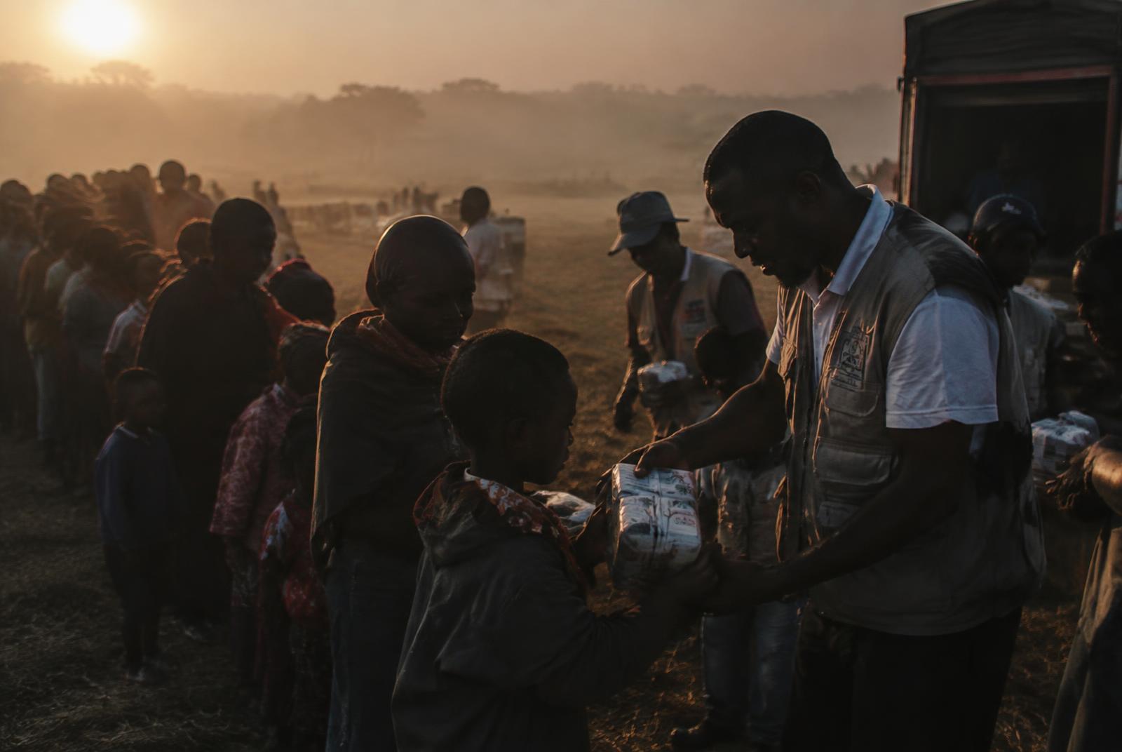 Volunteers handing out supplies to a community at sunrise